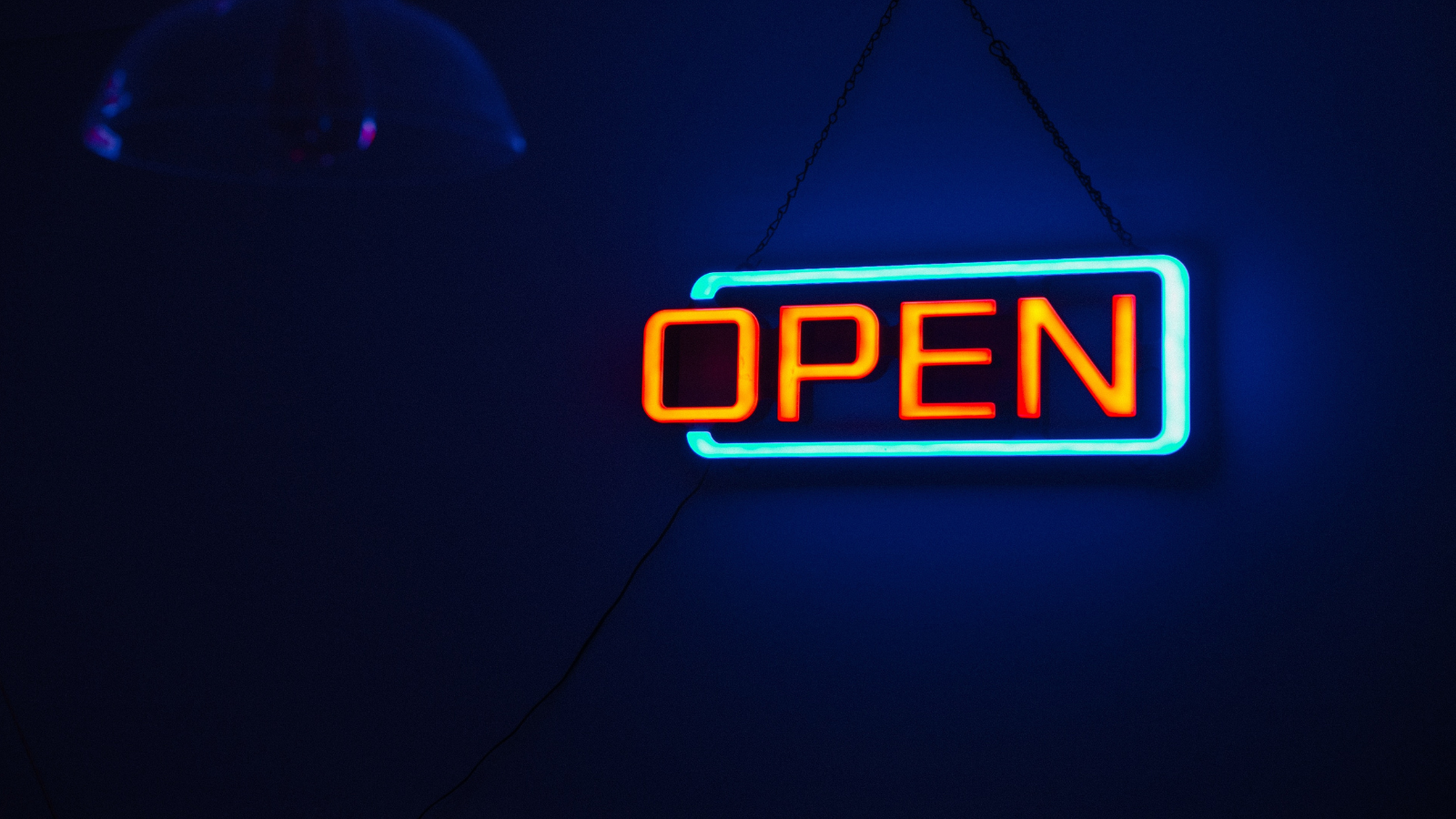A neon "open" sign often seen outside businesses glows in the corner of a dark room